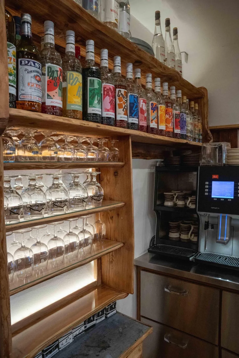 Bar en bois avec bouteilles Morand et verres éclairés