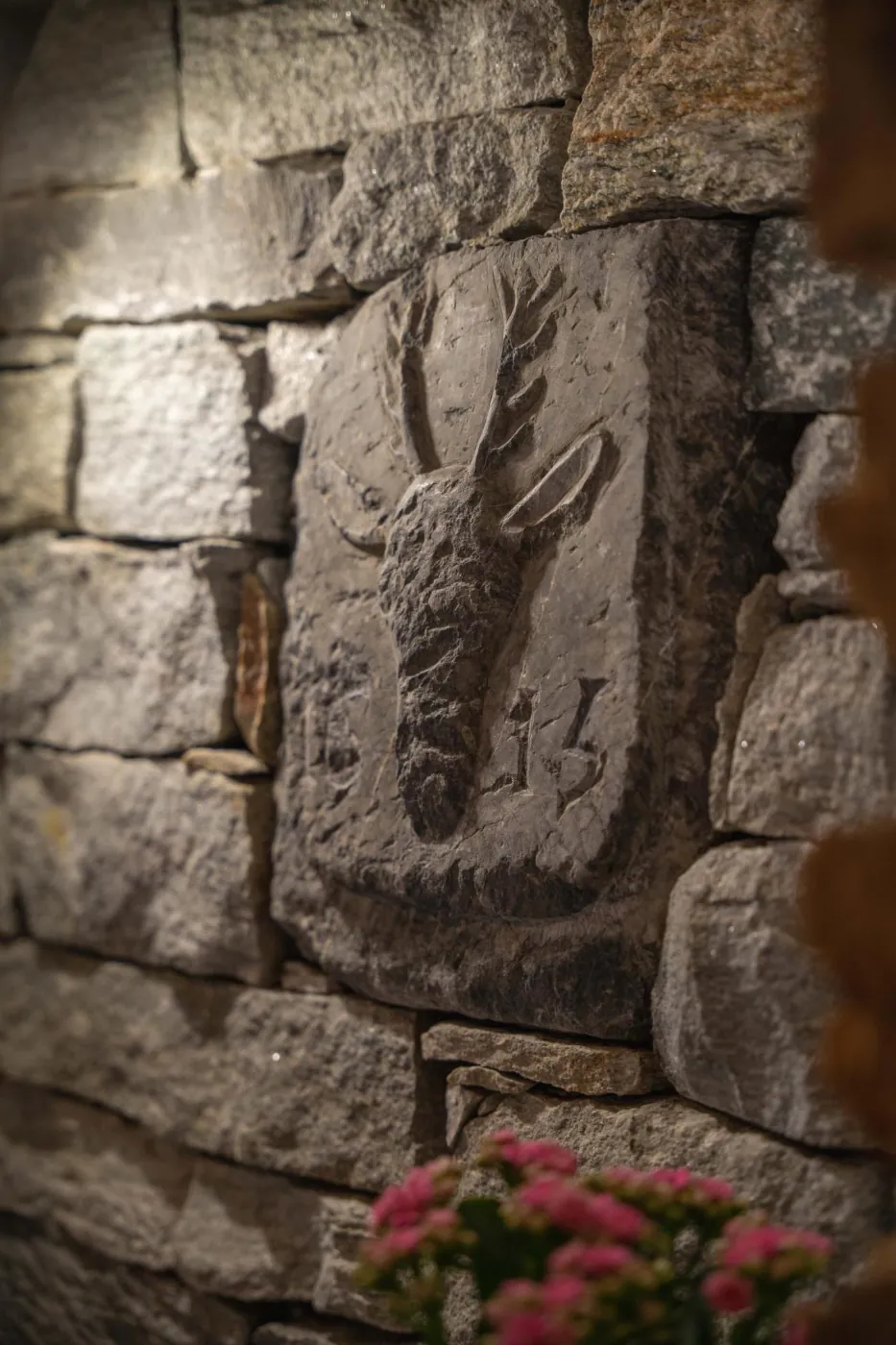 Cerf sculpté en pierre sur un mur en pierres apparentes